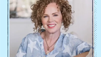 A woman with short curly hair and a blue and white shirt.