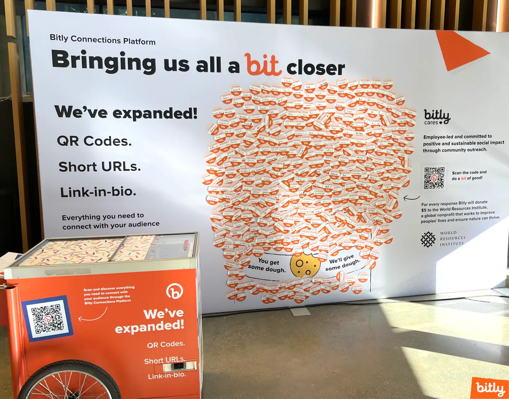 A Bitly exhibition booth with an orange cart in front of it.