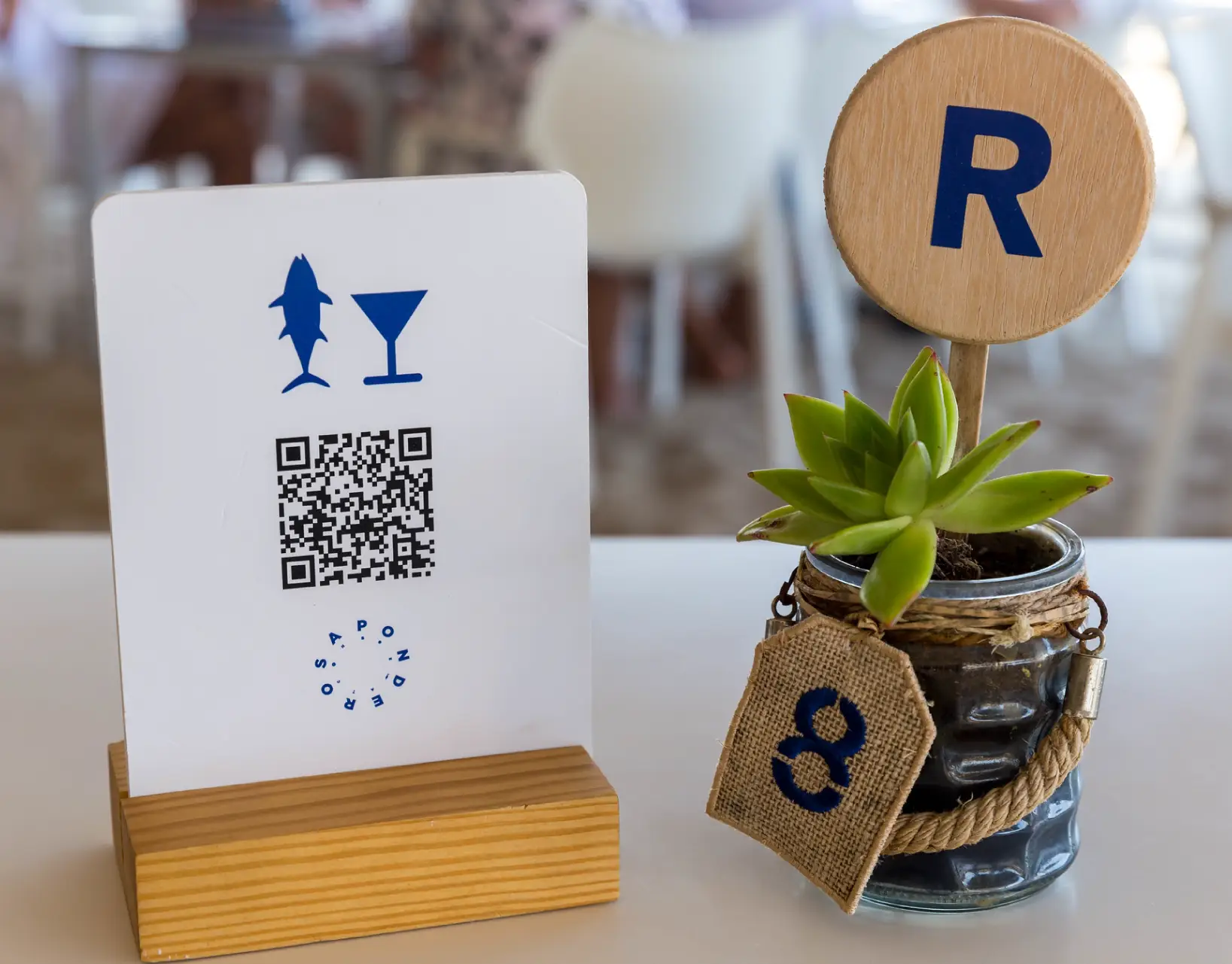 A QR Code table tent next to a small potted plant.
