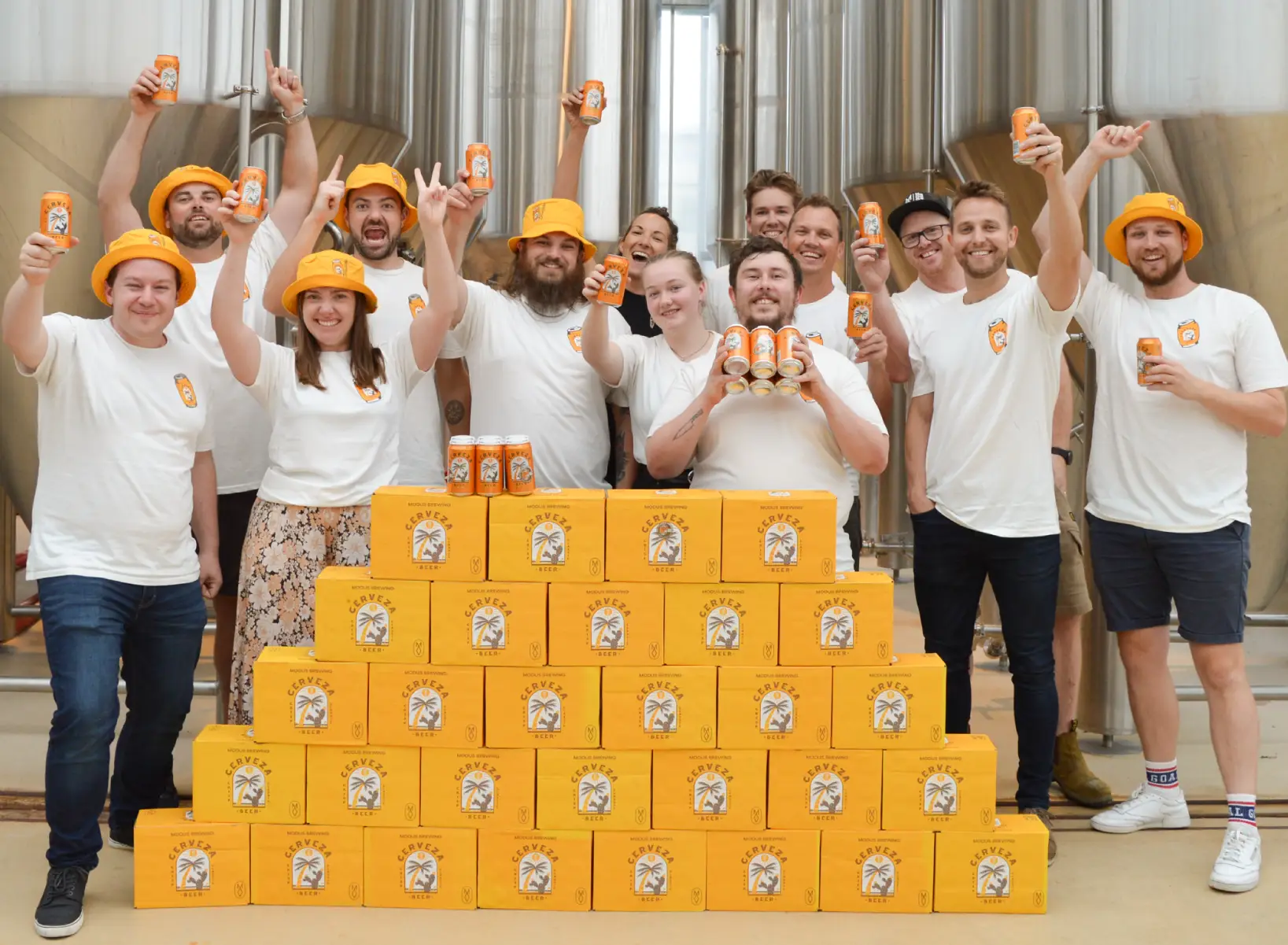 A group of smiling people standing in front of many cases of beer.