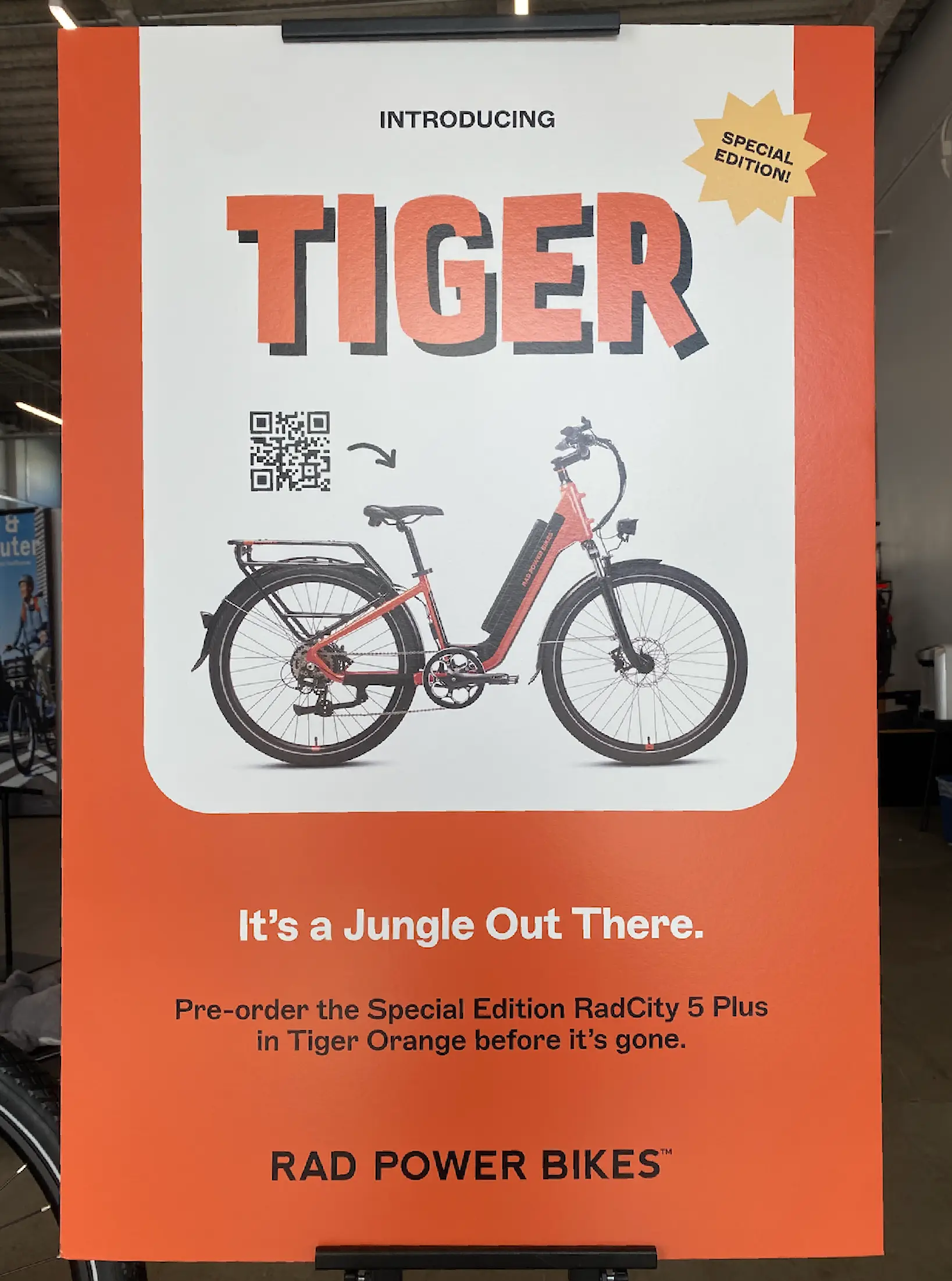 In-store poster at Rad Power Bikes promoting its Tiger Orange e-bike pre-order with a QR Code.