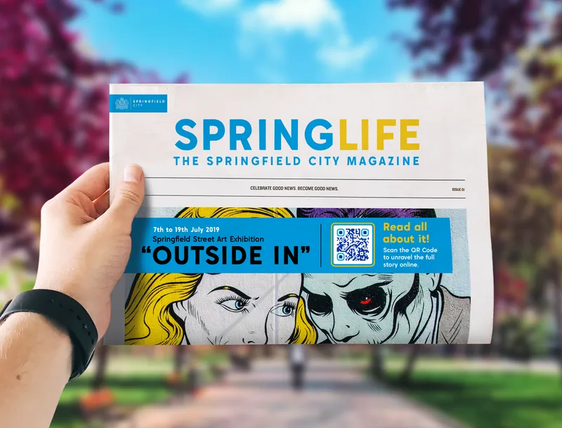 A person holding Spring Life magazine that has a QR Code printed on it.