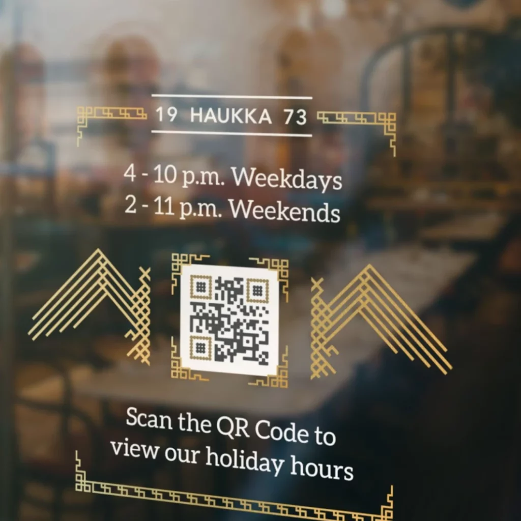 A restaurant window with its store hours and a black and gold QR Code surrounded by golden patterns on it