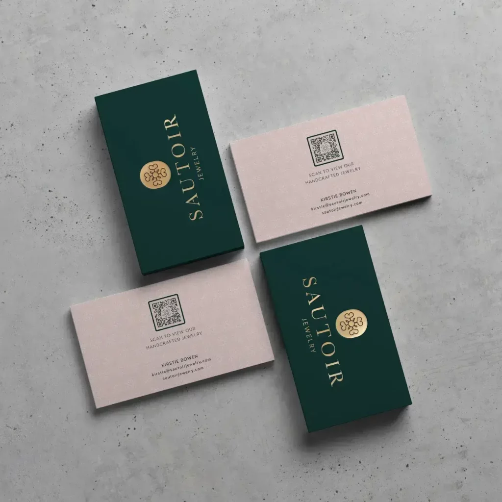 The backs and fronts of green and pink business cards with QR Codes on top with a golden font and logo