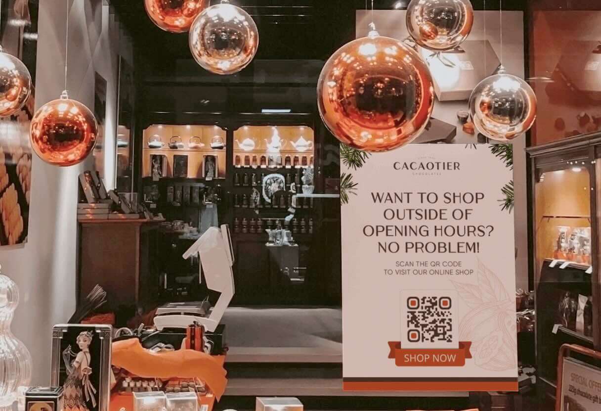 A shop with a poster displaying a QR Code and a “Shop now” frame printed on it.