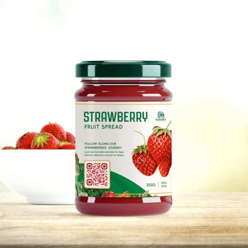 A bowl of strawberries next to a strawberry jam jar with a label that has a QR Code printed on it.